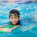 young boy swimming with flutter board