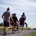 a person being transported by two other people on an adapted bike