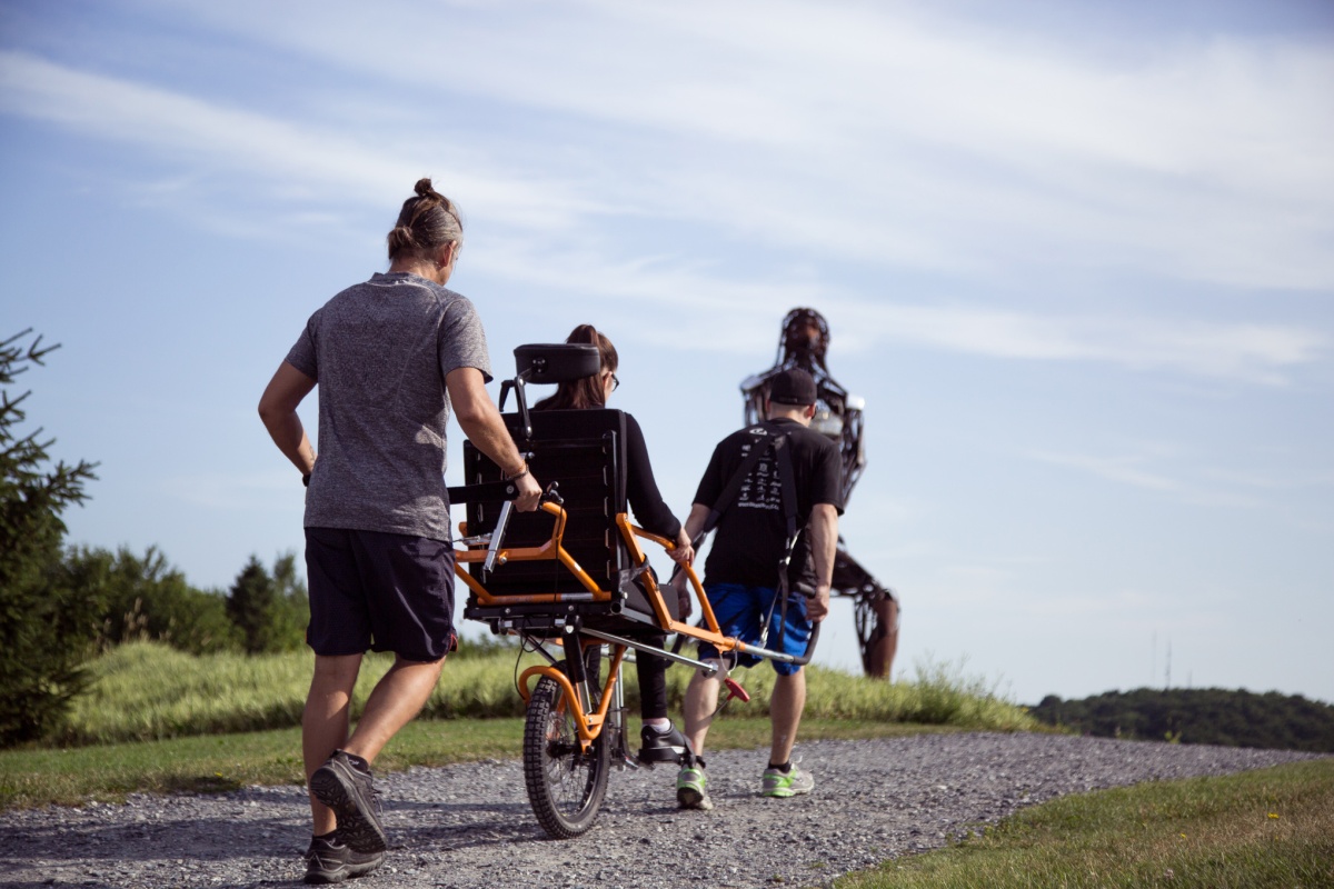 a person being transported by two other people on an adapted bike